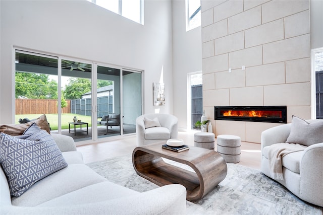 living room featuring wood-type flooring, plenty of natural light, and a tiled fireplace