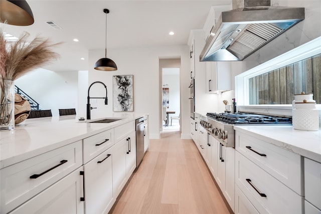 kitchen featuring light wood-type flooring, premium range hood, light stone counters, hanging light fixtures, and white cabinetry