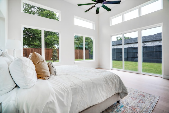 bedroom with a towering ceiling, ceiling fan, and hardwood / wood-style flooring