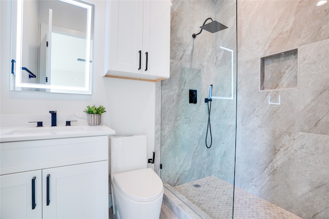 bathroom with tiled shower, vanity, and toilet