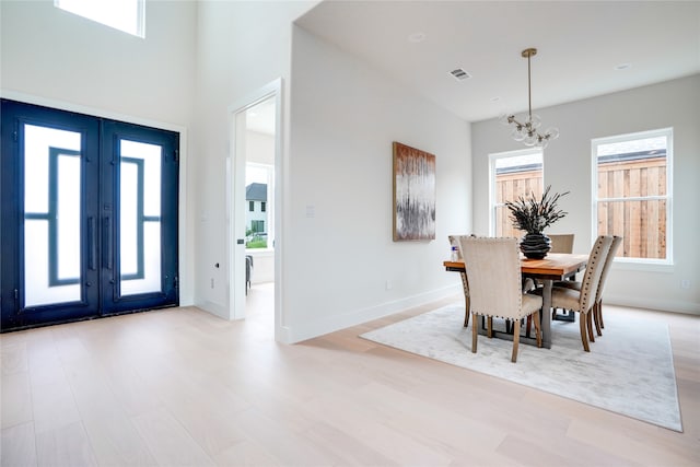 dining room featuring a notable chandelier, a wealth of natural light, light hardwood / wood-style floors, and french doors