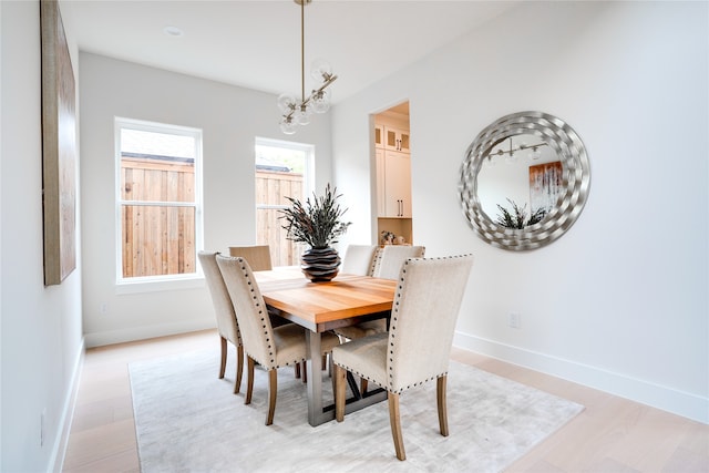 dining space with light hardwood / wood-style flooring and an inviting chandelier