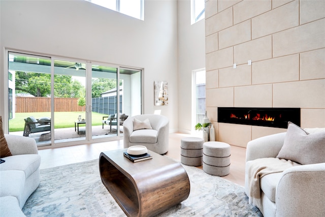 living room with a towering ceiling and a tile fireplace