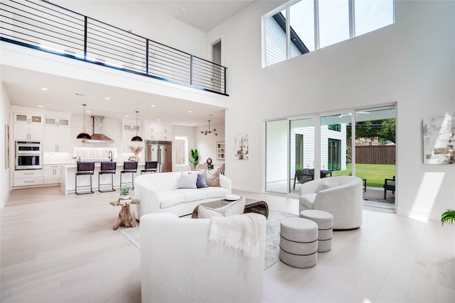 living room featuring a high ceiling, light hardwood / wood-style floors, and a chandelier