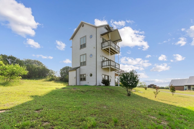 back of property featuring a balcony and a yard