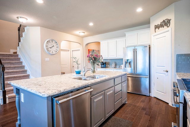 kitchen with white cabinetry, stainless steel appliances, decorative backsplash, dark hardwood / wood-style floors, and a center island with sink