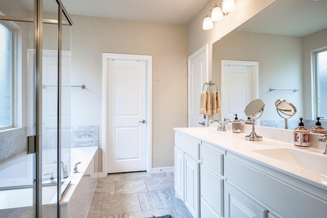 bathroom featuring a garden tub, a sink, and a healthy amount of sunlight