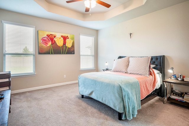 bedroom featuring ceiling fan, carpet, and a tray ceiling