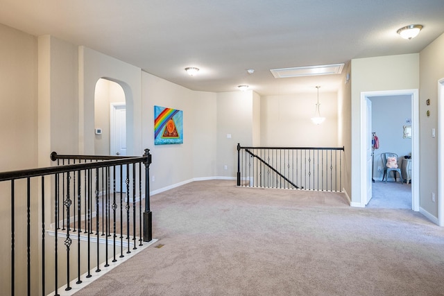 corridor with baseboards, carpet, attic access, and an upstairs landing