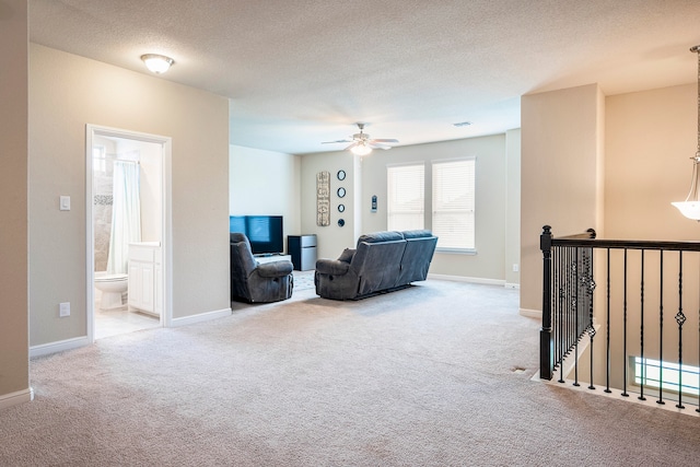 sitting room with a textured ceiling, light colored carpet, and ceiling fan