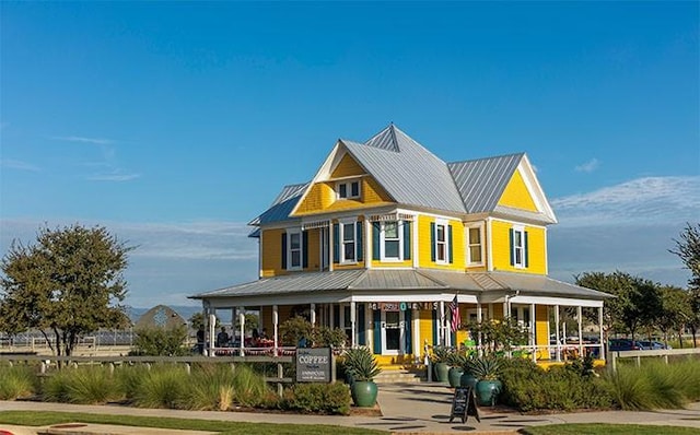 back of house featuring covered porch and metal roof