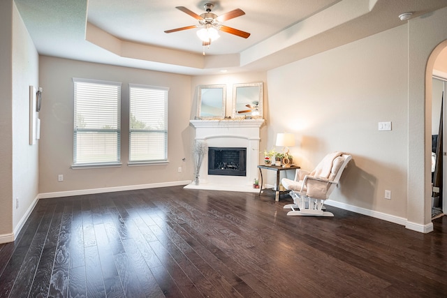 unfurnished living room with ceiling fan, a tray ceiling, and hardwood / wood-style flooring