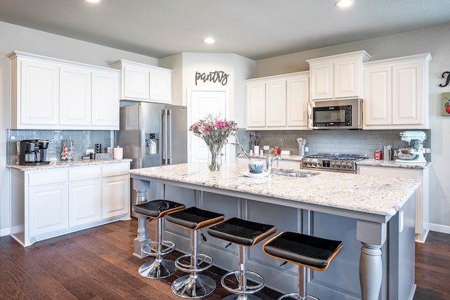 kitchen featuring dark wood-type flooring, appliances with stainless steel finishes, tasteful backsplash, and white cabinetry