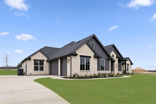 view of front of property featuring a garage, a front lawn, and central air condition unit