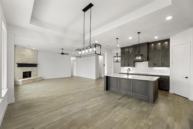 kitchen featuring decorative light fixtures, sink, dark brown cabinetry, and a kitchen island with sink