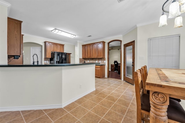 kitchen featuring black refrigerator with ice dispenser, hanging light fixtures, ornamental molding, light tile patterned flooring, and kitchen peninsula