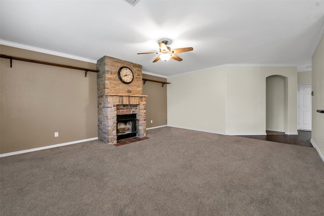 unfurnished living room with a fireplace, dark colored carpet, ceiling fan, and crown molding