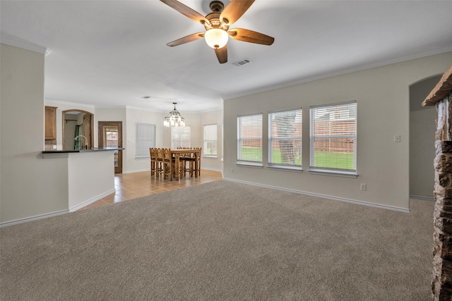 unfurnished living room featuring crown molding, light carpet, and ceiling fan with notable chandelier