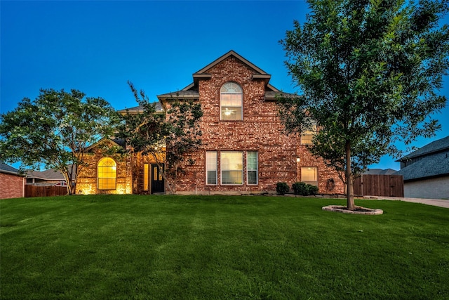 traditional home with a front lawn, brick siding, and fence