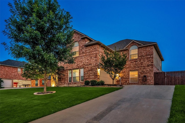 traditional-style house with fence, a front lawn, driveway, and brick siding