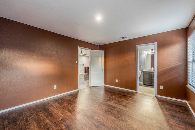 unfurnished bedroom with connected bathroom and dark hardwood / wood-style floors