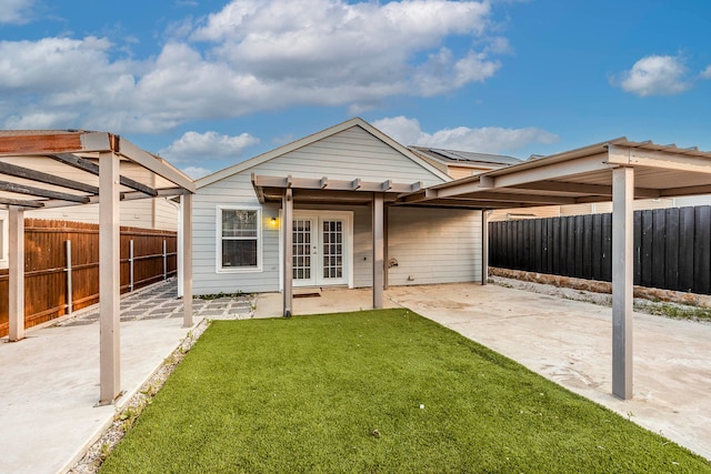 rear view of property with a lawn, a patio area, and french doors