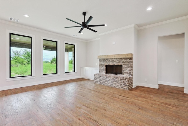 unfurnished living room with crown molding, a brick fireplace, and light hardwood / wood-style floors