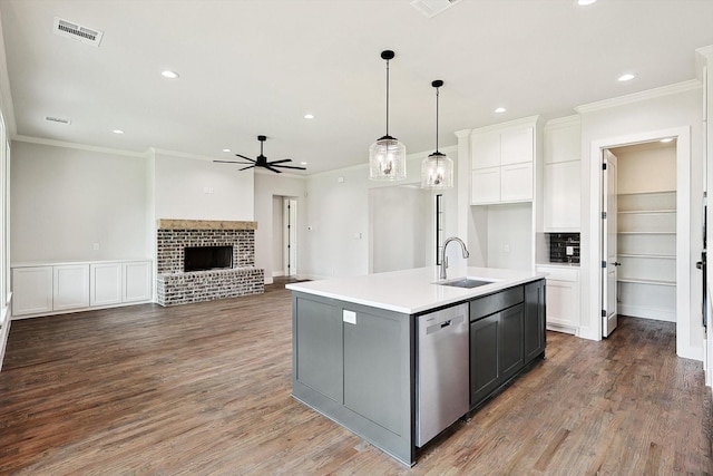 kitchen featuring pendant lighting, sink, dishwasher, white cabinetry, and a center island with sink