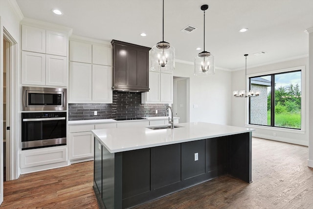 kitchen with sink, white cabinetry, a center island with sink, appliances with stainless steel finishes, and dark hardwood / wood-style flooring