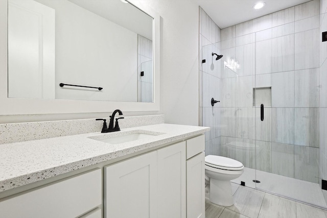 bathroom with vanity, toilet, and a shower with door