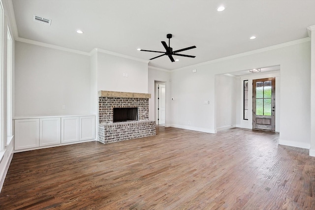 unfurnished living room featuring crown molding, ceiling fan, dark hardwood / wood-style flooring, and a brick fireplace