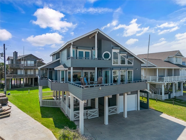 rear view of house with a garage, a balcony, and a lawn