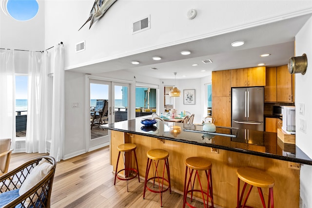 kitchen featuring kitchen peninsula, a kitchen bar, light hardwood / wood-style floors, and stainless steel fridge