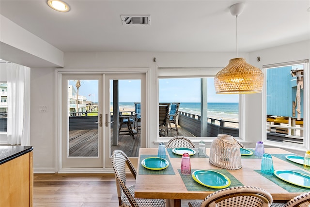 dining area featuring wood-type flooring, plenty of natural light, and a water view