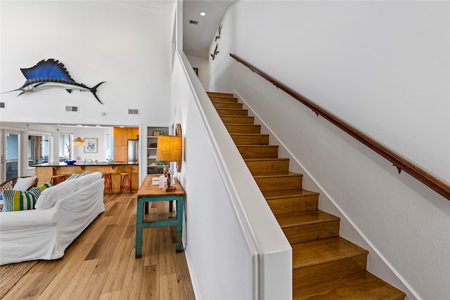 staircase with a high ceiling and light wood-type flooring