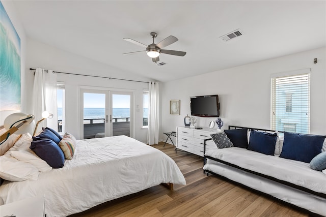 bedroom featuring multiple windows, wood-type flooring, vaulted ceiling, and a water view