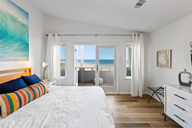 bedroom featuring lofted ceiling, a water view, access to exterior, and hardwood / wood-style flooring