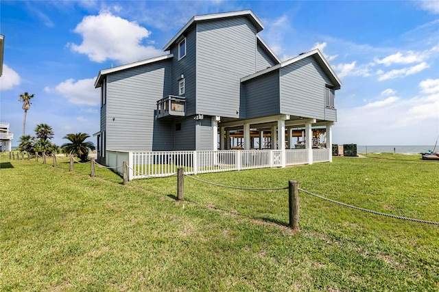 rear view of property featuring a lawn and a water view