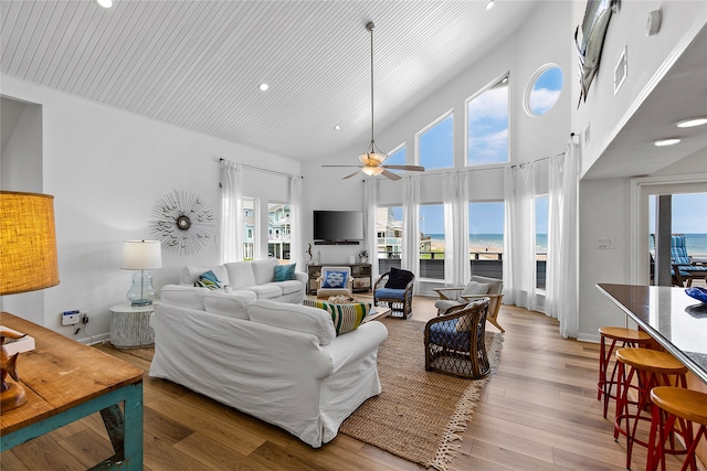 living room with wood-type flooring, ceiling fan, high vaulted ceiling, and a water view