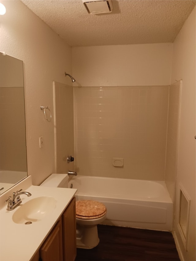 full bathroom featuring toilet, tub / shower combination, large vanity, and a textured ceiling