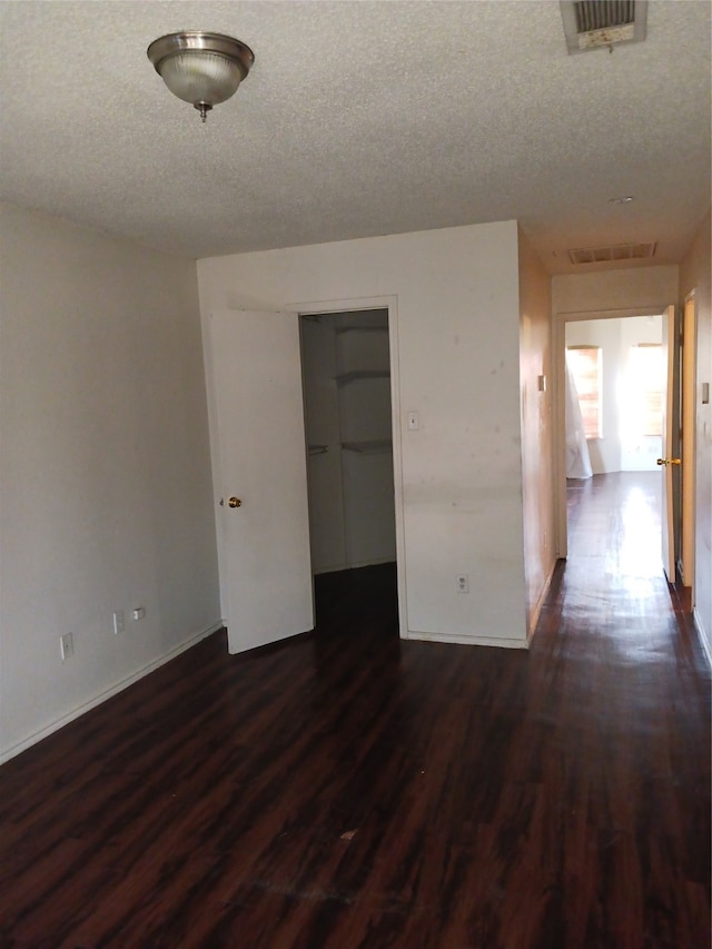 spare room with a textured ceiling and dark hardwood / wood-style flooring