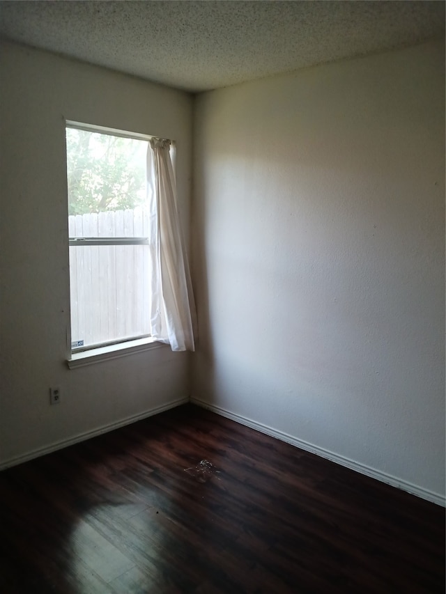 spare room featuring a textured ceiling and dark wood-type flooring