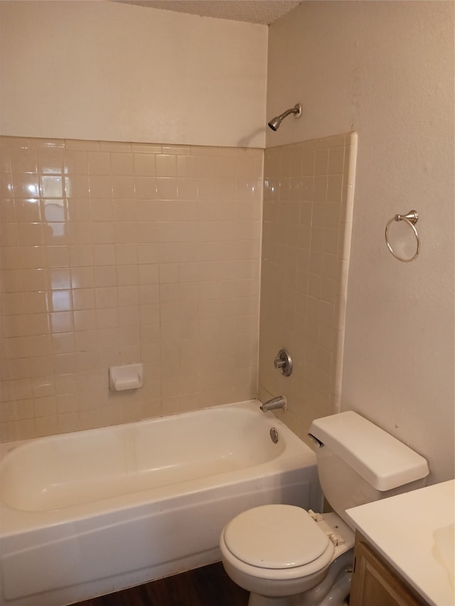 full bathroom with tiled shower / bath combo, toilet, vanity, and a textured ceiling