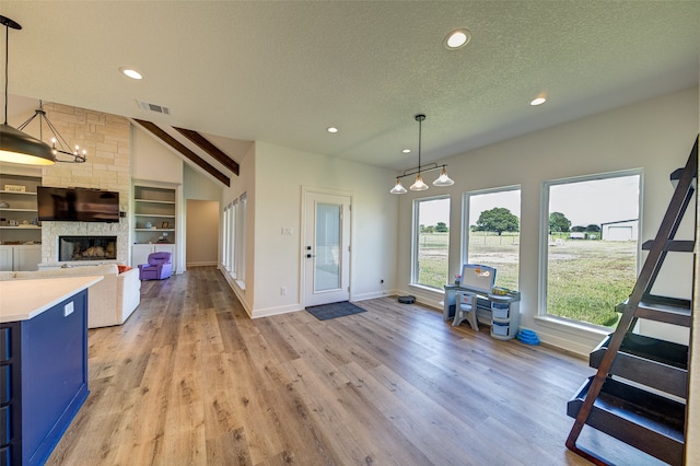 kitchen featuring decorative light fixtures, light hardwood / wood-style floors, a fireplace, a notable chandelier, and a textured ceiling