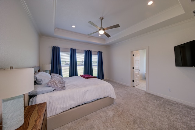 bedroom with carpet, ceiling fan, a tray ceiling, and ensuite bathroom