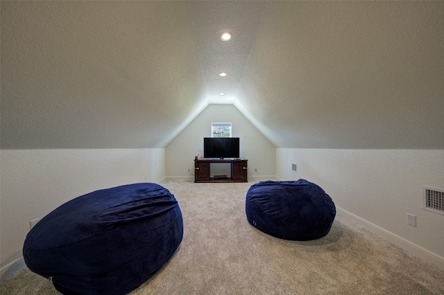 sitting room with carpet floors, a textured ceiling, and lofted ceiling