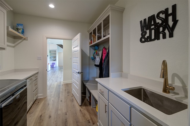 kitchen with sink, range, light wood-type flooring, and white cabinetry