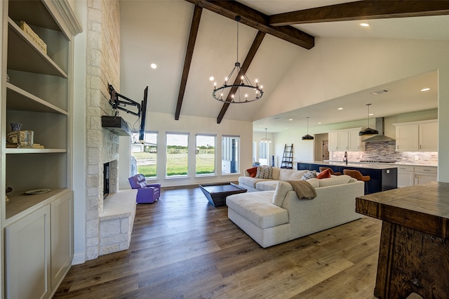 living room featuring a stone fireplace, beam ceiling, wood-type flooring, high vaulted ceiling, and a chandelier