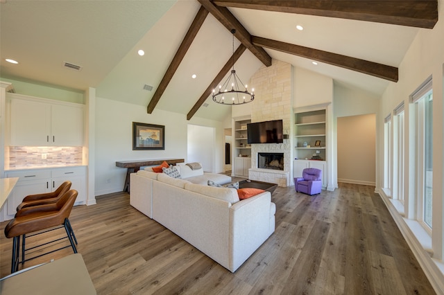 living room with beamed ceiling, a chandelier, a fireplace, and wood-type flooring