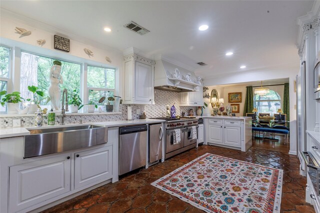 kitchen with kitchen peninsula, white cabinetry, ornamental molding, sink, and stainless steel appliances